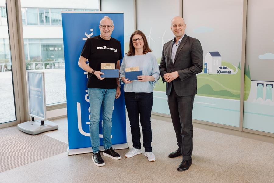 Zwei Gewinner:innen erhalten ihre Gutscheine vom kaufmännischen Leiter Mathis Broelmann überreicht. 