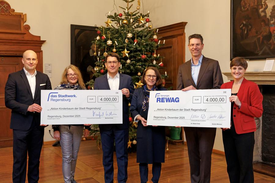 Vor dem geschmückten Christbaum im Alten Rathaus übergaben Stadtwerk-Geschäftsführer Manfred Koller, kfm. Leiter Mathis Broelmann, die REWAG-Vorstände Robert Greb und Sandra Wimmer zwei große Spendenschecks an Oberbürgermeisterin Gertrud Maltz-Schwarzfischer und Christiana Schmidbauer von der Aktion Kinderbaum.