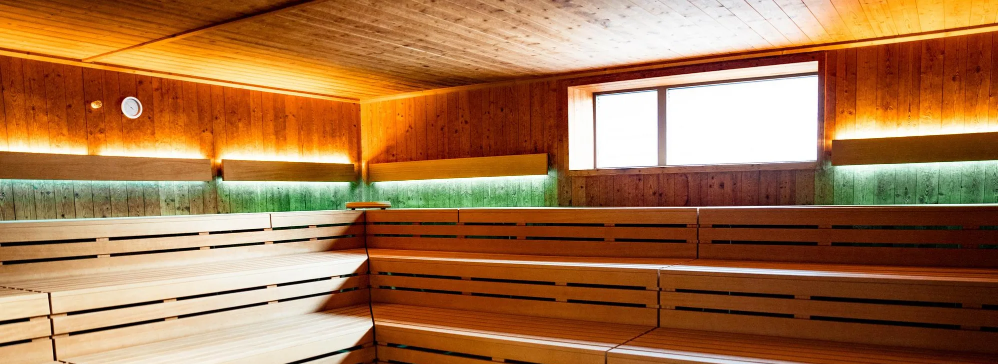 Innenraum einer Sauna mit mehrstufigen Holzbänken und indirekter Beleuchtung