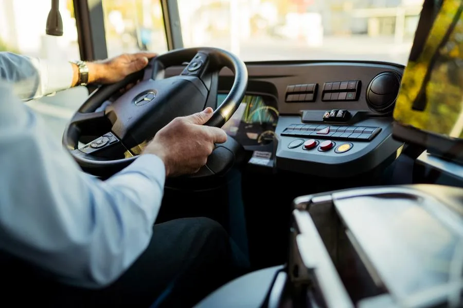 Fahrerarbeitsplatz eines Linienbusses mit Lenkrad, Bedienelementen und Frontscheibe.