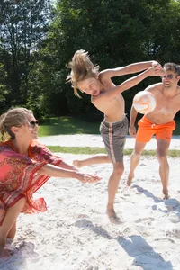 Junge Erwachsene mit einem Jungen beim Beachvolleyball spielen