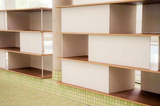 Moderne Regale mit weißen Fächern und Holzablagen in einem Raum mit grün gekacheltem Boden