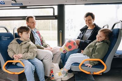 Familie mit zwei Kindern fährt mit dem Bus zum Spielplatz