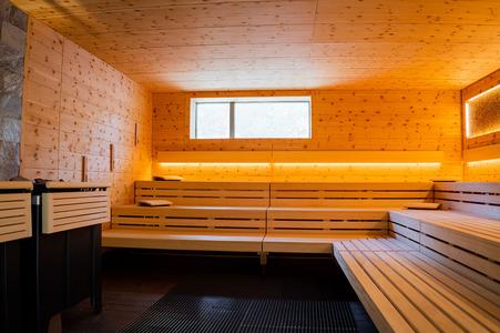 Innenraum einer Sauna mit Holzverkleidung, mehrstufigen Holzbänken und einem Fenster oberhalb der Bänke