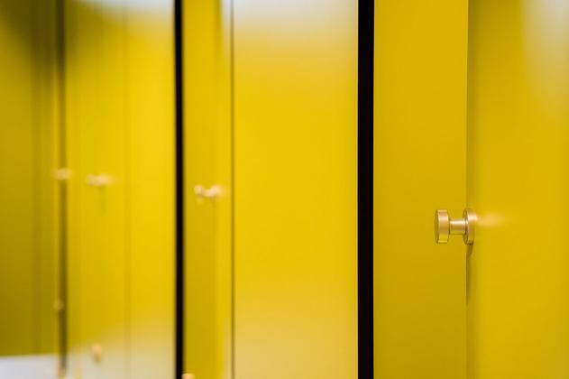 Reihe gelber Spindtüren mit runden Metallgriffen in einem Sportpark