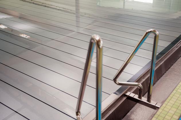 Schwimmbecken mit Edelstahl-Handlauf und abgedeckter Wasseroberfläche