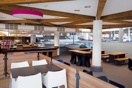 Innenbereich des Westbads mit Sitzbereichen, Tischen und Blick auf das Schwimmbecken