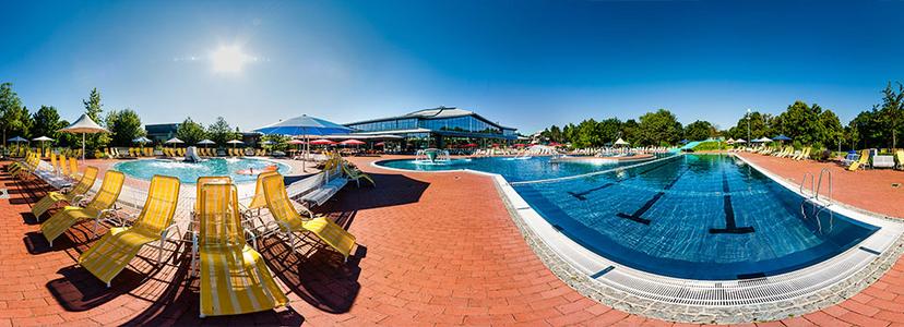 Panorama des Westbads Regensburg mit Außenbecken, Liegestühlen und sonnigem Himmel