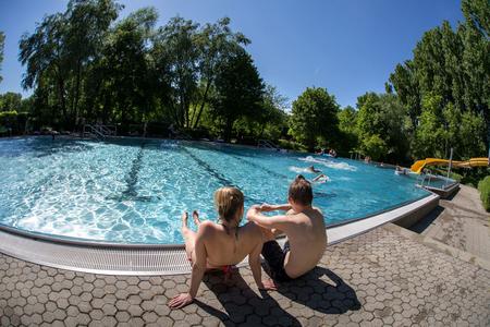 Zwei Kinder sitzen am Erlebnisbecken mit Strömungskanal und einer gelbe Rutsche