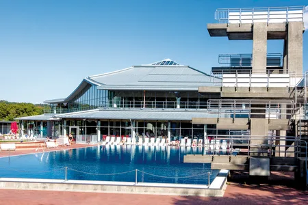 Außenansicht des Westbads mit großem Schwimmbecken und hohem Sprungturm bei klarem Himmel