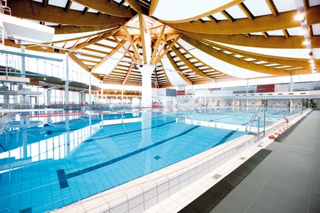 Großes Hallenbad mit Holztragwerk und mehreren Schwimmbahnen im Westbad